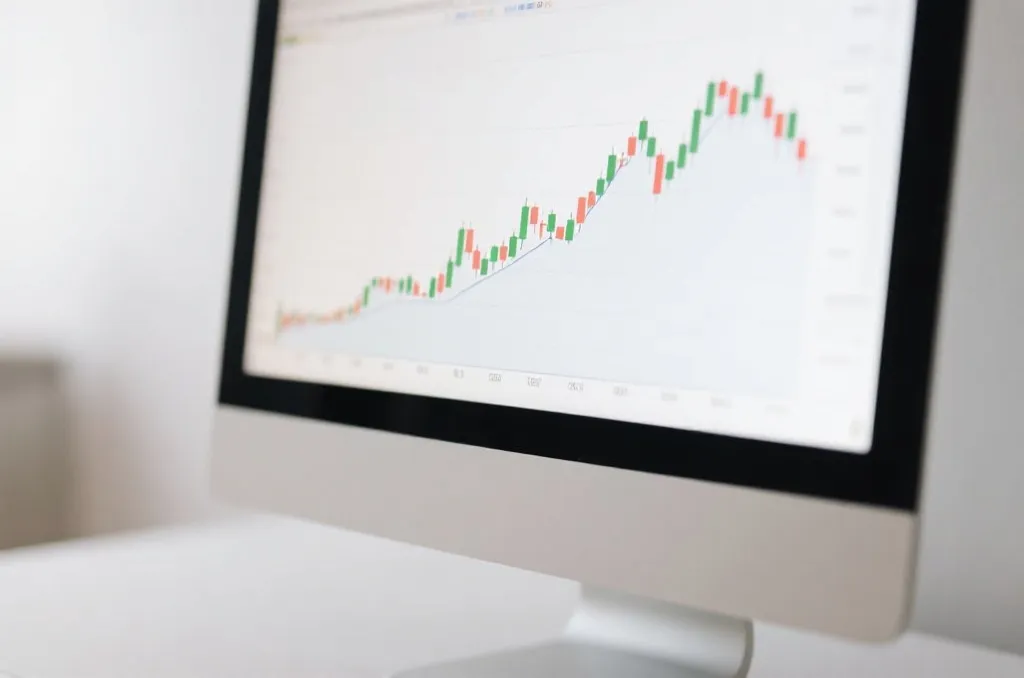 A clean financial-style candlestick chart on a computer monitor, simplified neutral design, soft lighting, no text, no branding, professional presentation